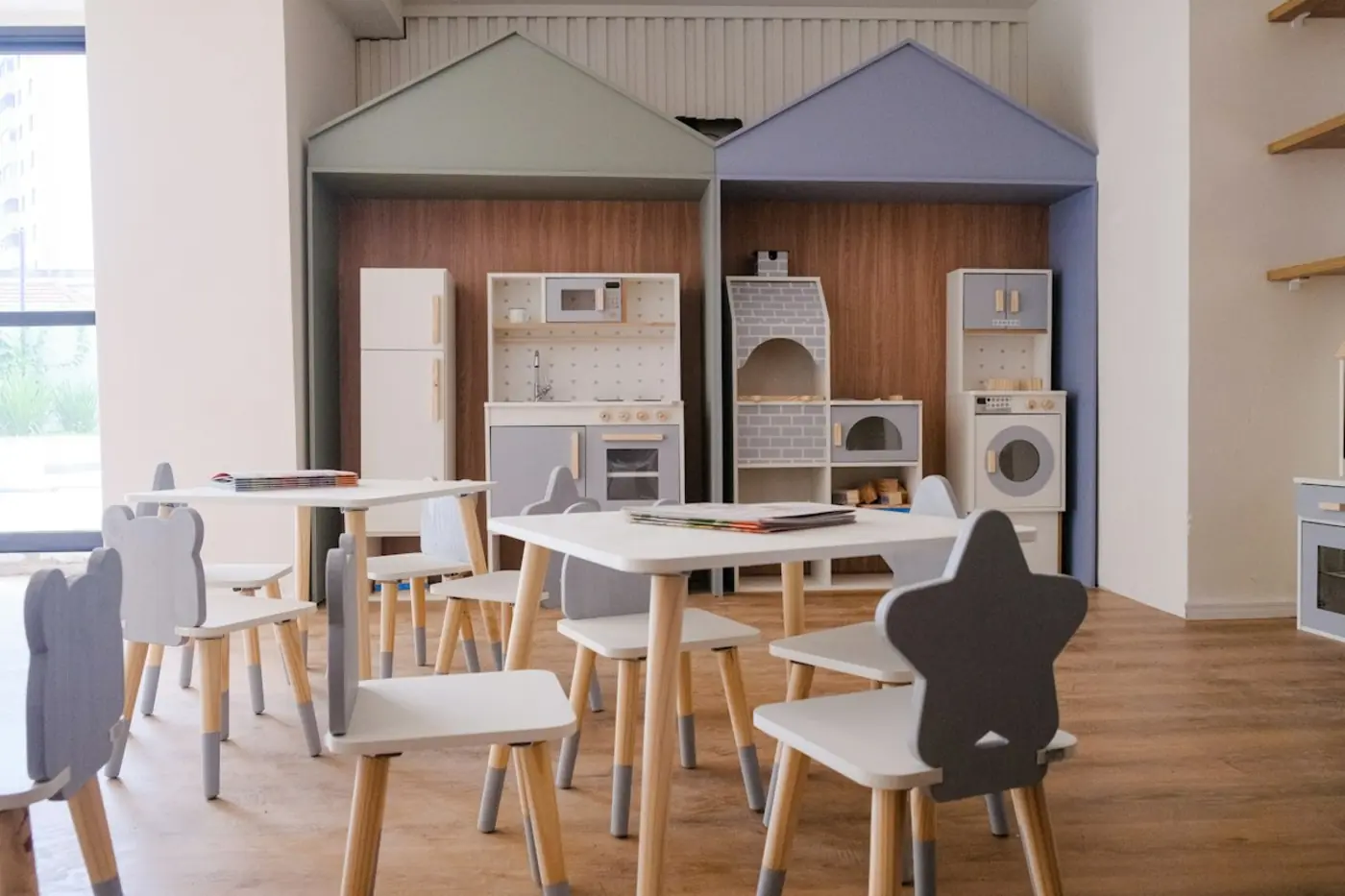 Espacio de juego con mesitas y una cocina de juguete de madera